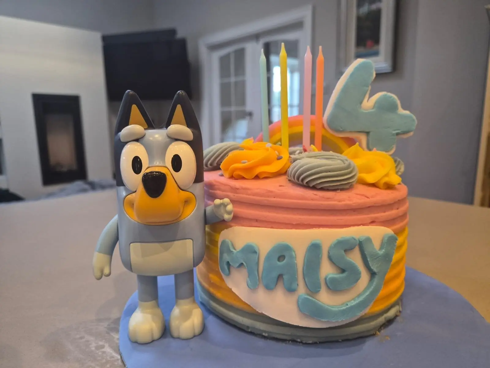 colourful fourth birthday cake decorated with pastel icing, rainbow topper and number four candle, personalised with the name Maisy and displayed beside a Bluey figure, celebrating down syndrome milestones and each meaningful developmental milestone achieved by children with Down syndrome