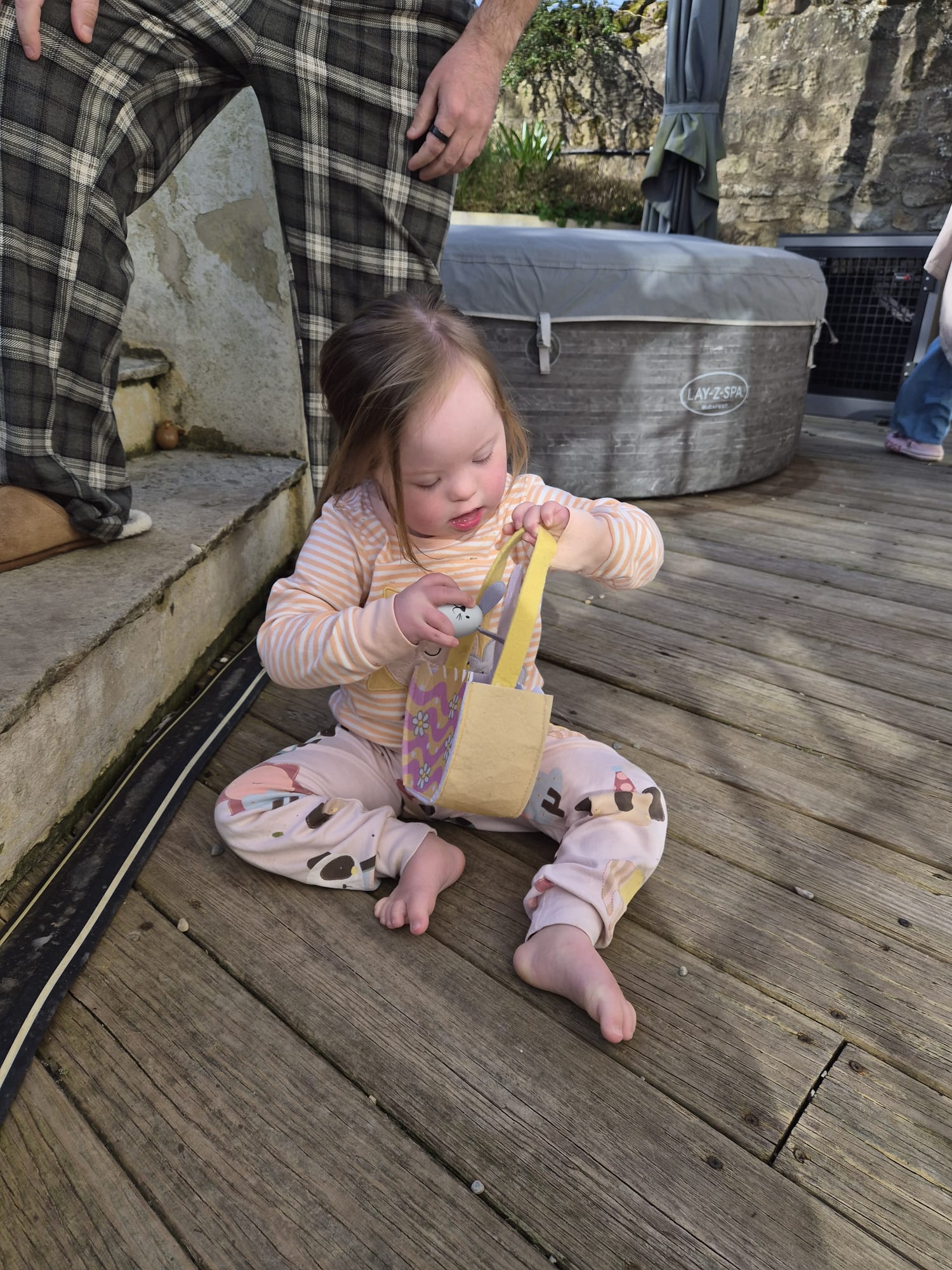toddler girl with down syndrome demonstrating her fine motor skills as she  explores items in a bag