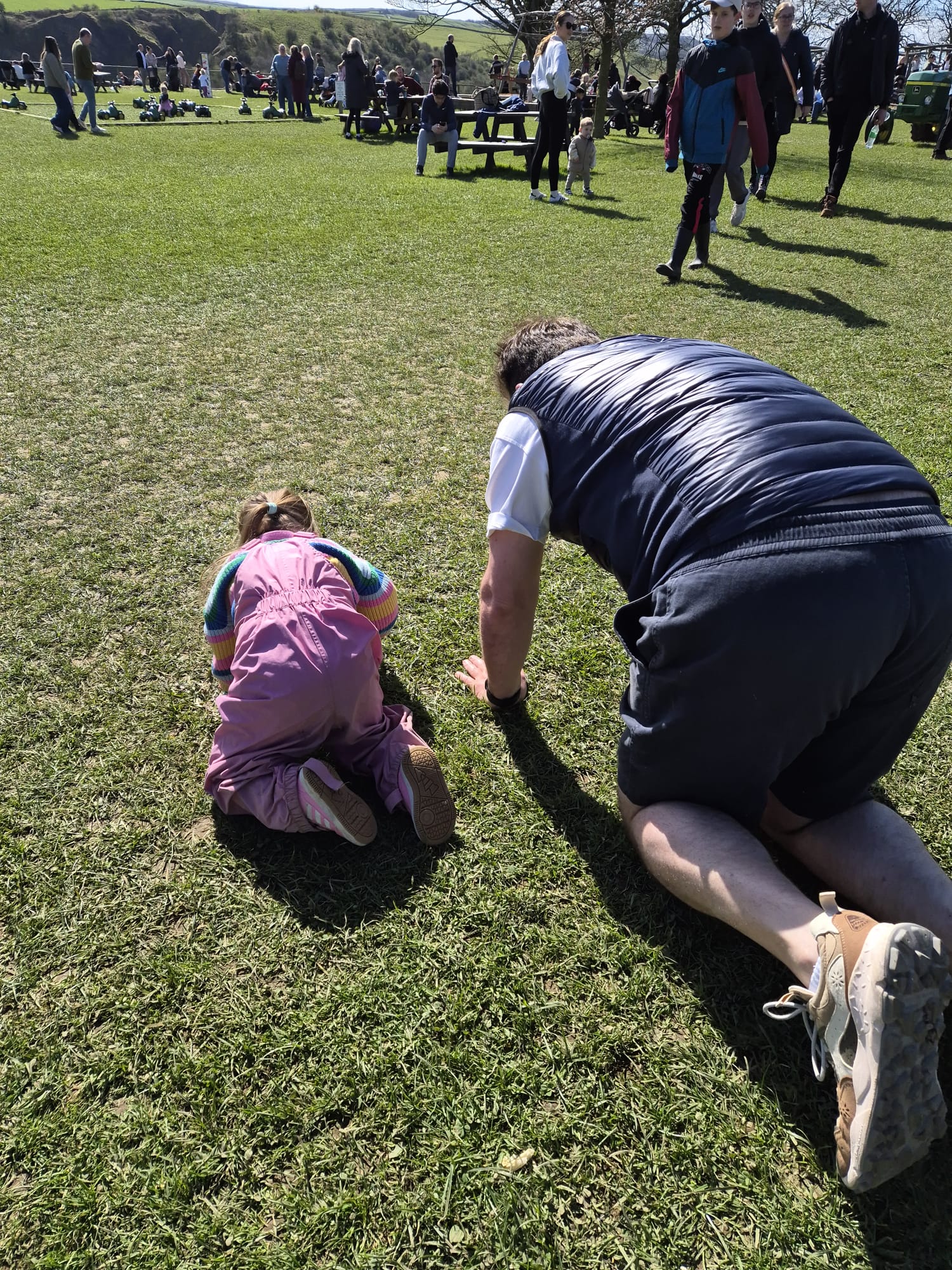 father crawling alongside his daughter with down syndrome practising crossing the midline which contributes to fine motor skill development
