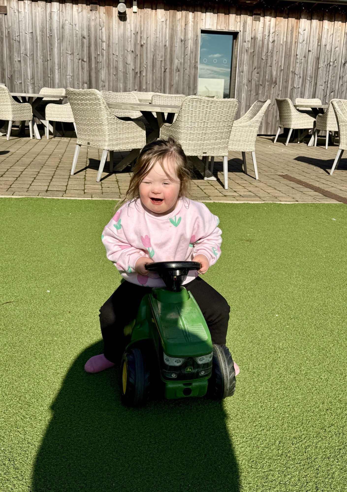 Child with Down syndrome using ride-on toy to build coordination, balance and motor skills while staying physically active through play