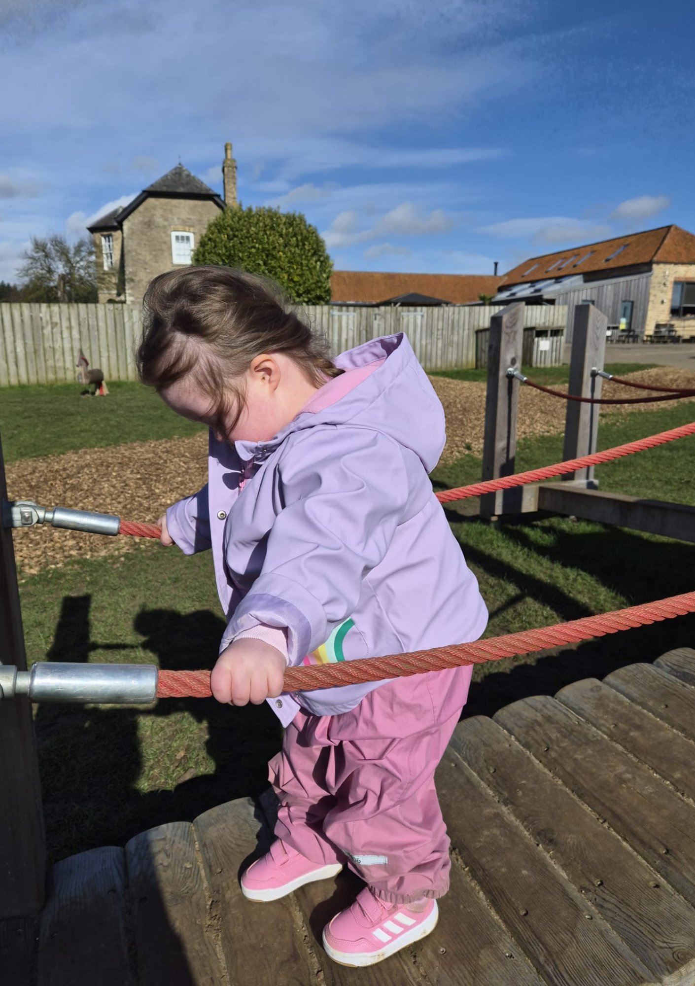 Toddler with Down syndrome holding rope for balance, developing hand strength, grasp and coordination through active play