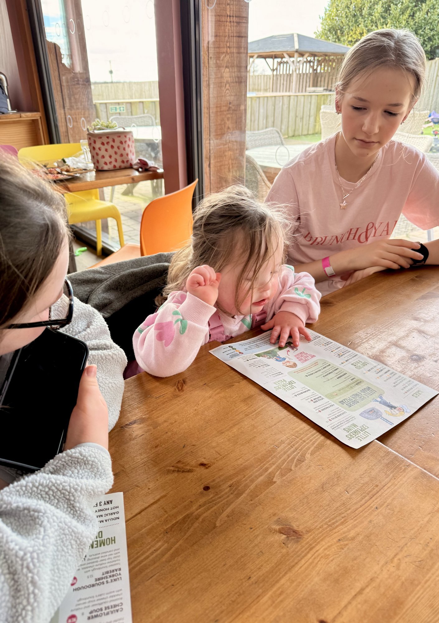 Child with Down syndrome reaching for paper on table, practising fine motor tasks, grasp and hand coordination with small objects