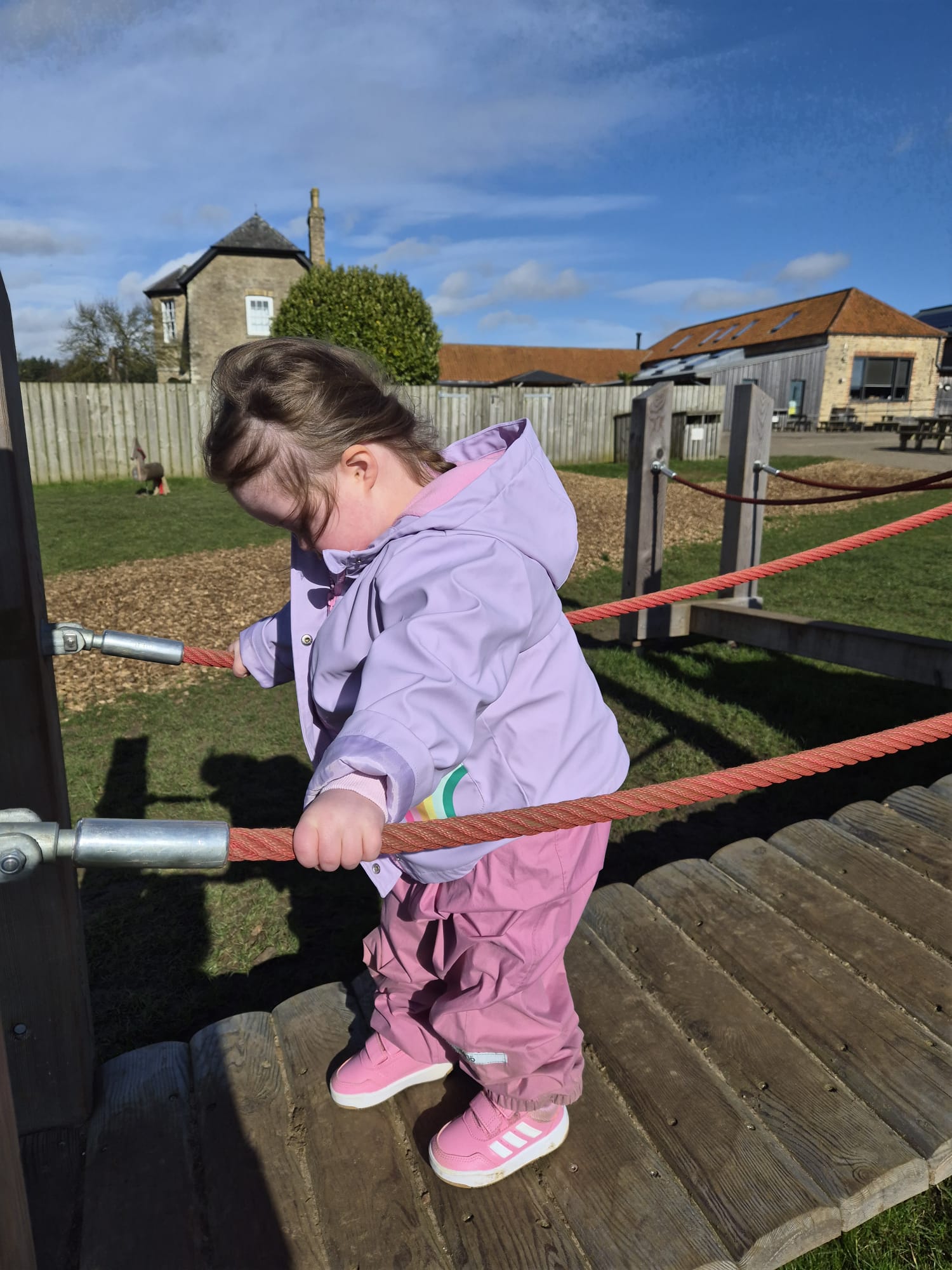 down syndrome toddler walking on a wooden bridge