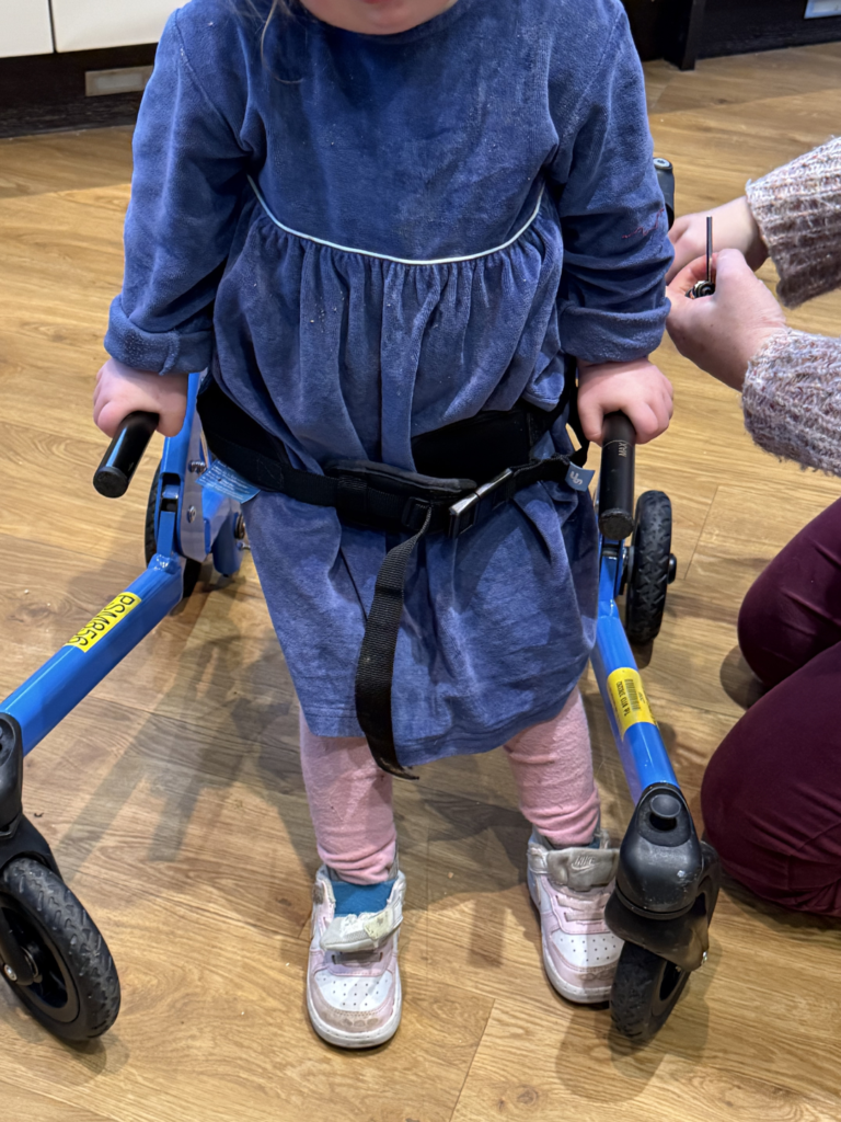 down syndrome toddler strenghtening her core muscles by using a walker to walk